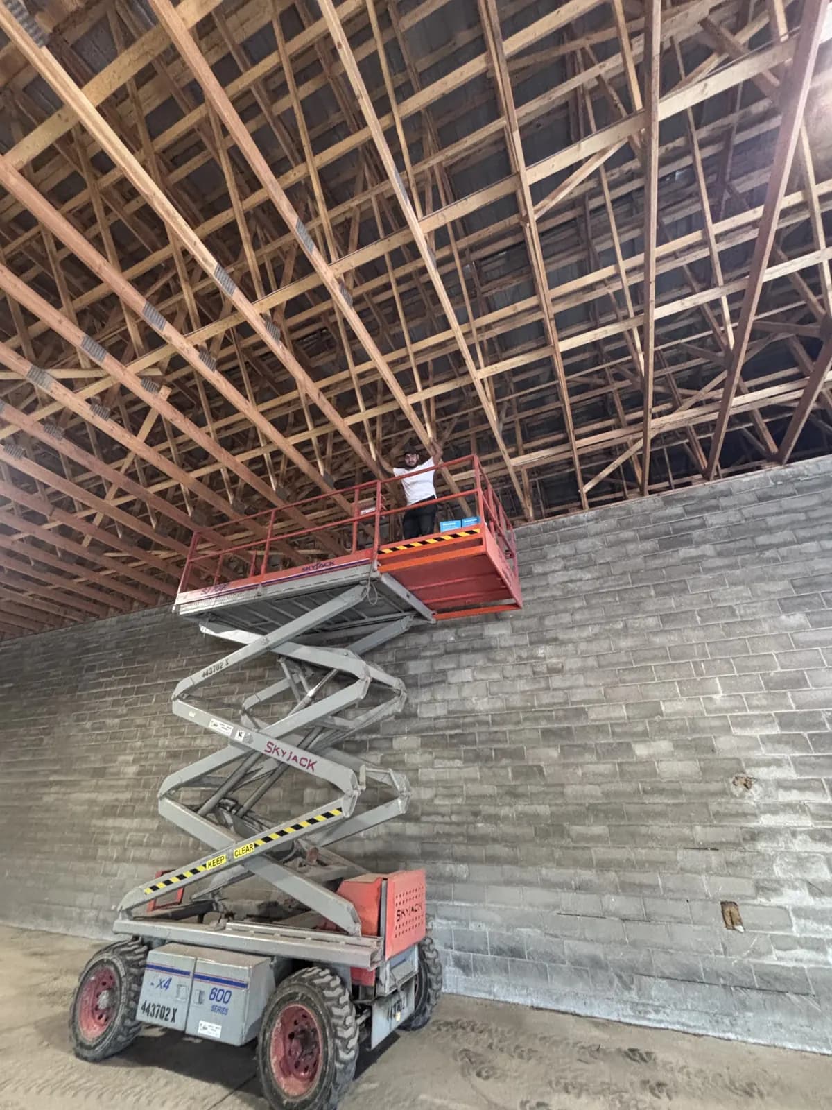 Scissor lift raised against a warehouse wall for high-mount camera installation
